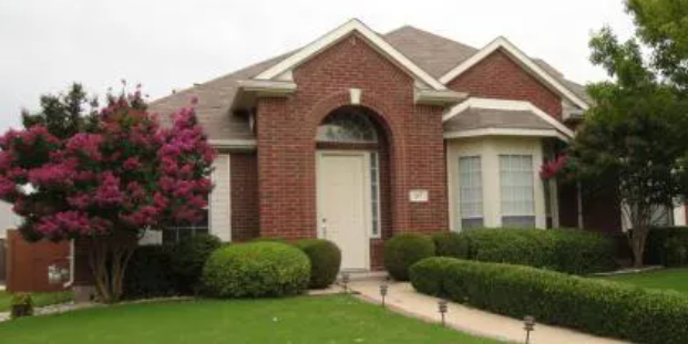 Red brick arched-entry home with crepe myrtle in Creekside, Murphy, Texas