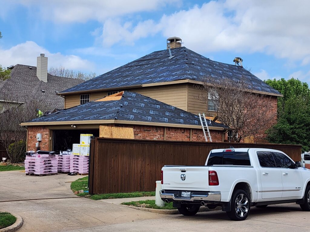 Roof replacement in progress on a two-story Allen, Texas home with underlayment and staged shingles