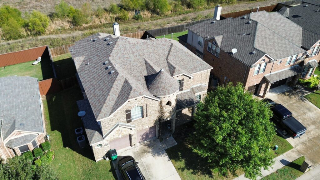 Aerial view of a two-story brick home with a turreted architectural-shingle hip roof in Celina, Texas