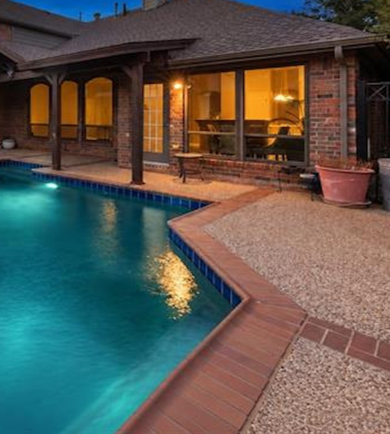 Brick home backyard pool at twilight in Highlands of Preston Ridge, Plano, Texas