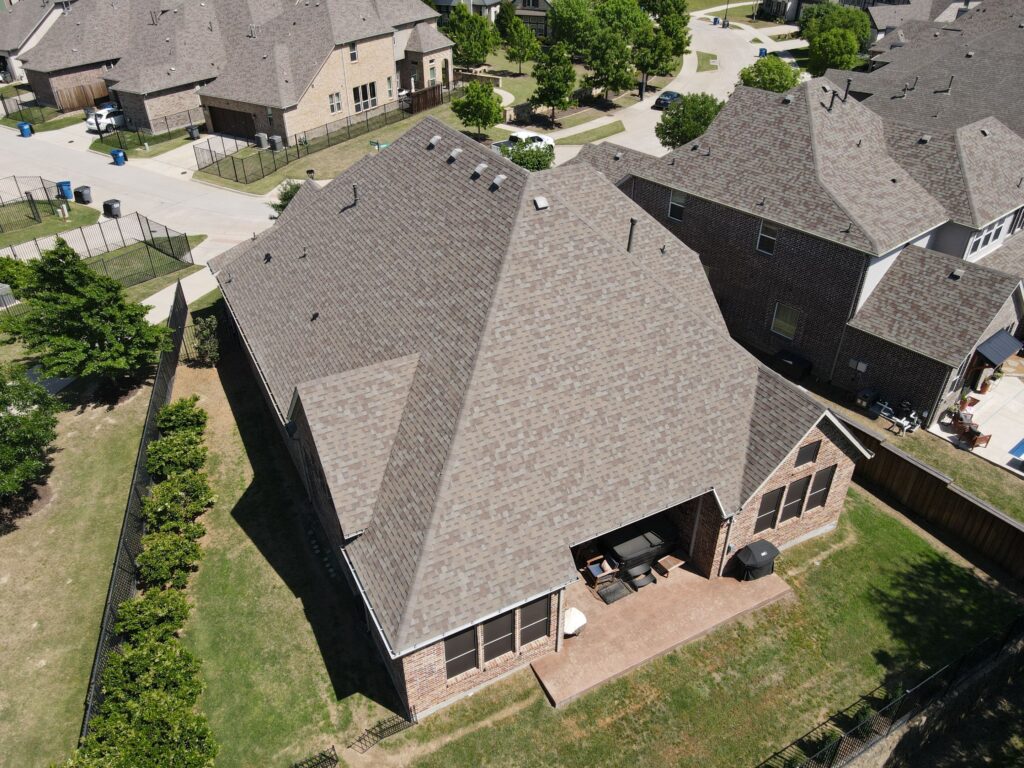 Aerial view of a completed hip-and-gable architectural shingle roof on an Allen, Texas brick home