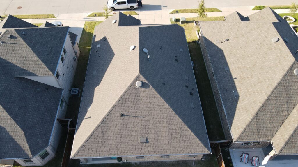 Overhead view of three neighboring architectural-shingle hip roofs in Celina, Texas