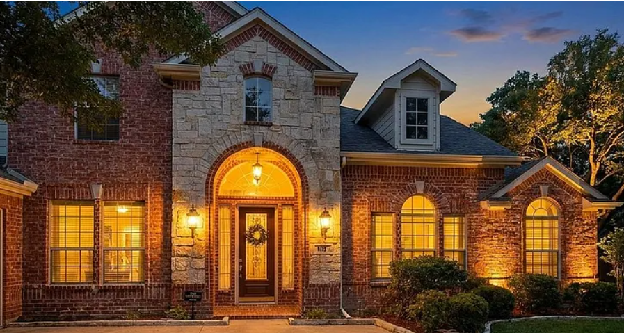 Brick and stone arched-entry luxury home at dusk in Hunters Landing, Murphy, Texas
