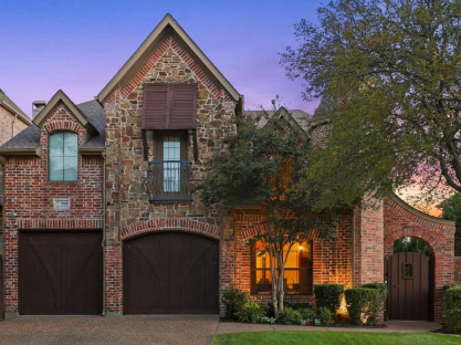 Two-story stone and brick home at dusk in Kings Ridge, Plano, Texas
