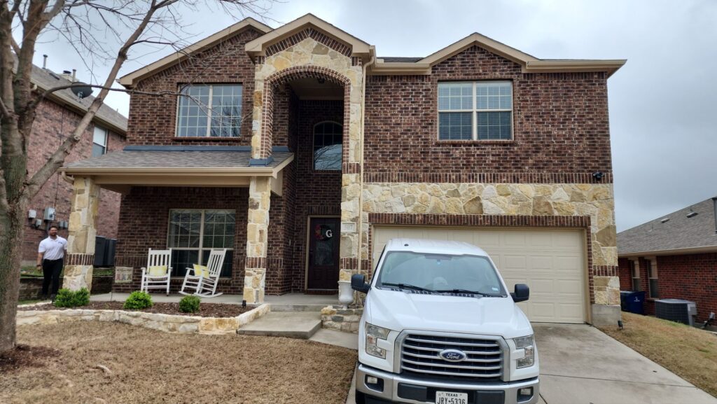 Front view of a two-story brick and stone home with a brown shingle roof in Celina, Texas