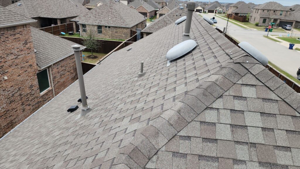 Close aerial view of a gray architectural-shingle hip roof with vents in a Celina, Texas neighborhood