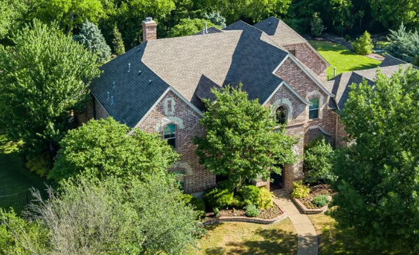 Multi-gable brick home under mature trees in Rolling Ridge Estates, Murphy, Texas