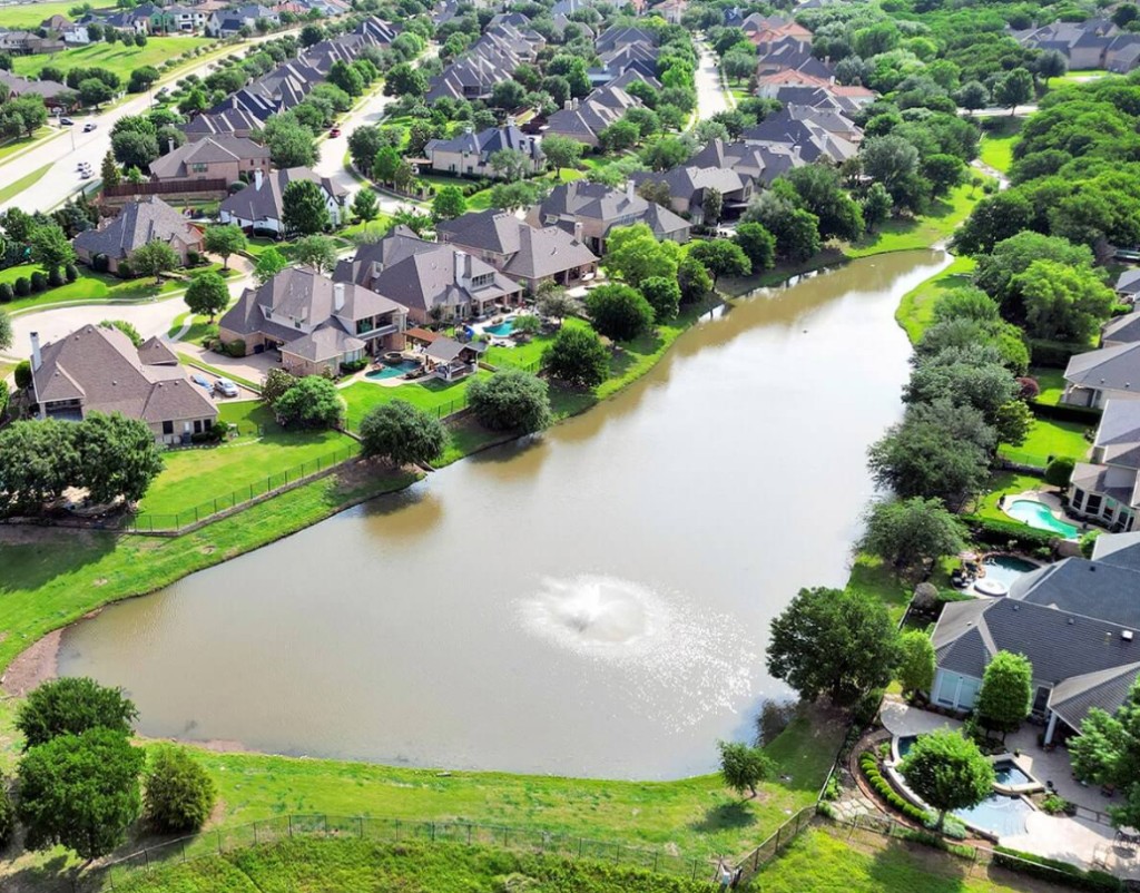 Aerial view of Starwood homes around a pond with fountain in Frisco, Texas