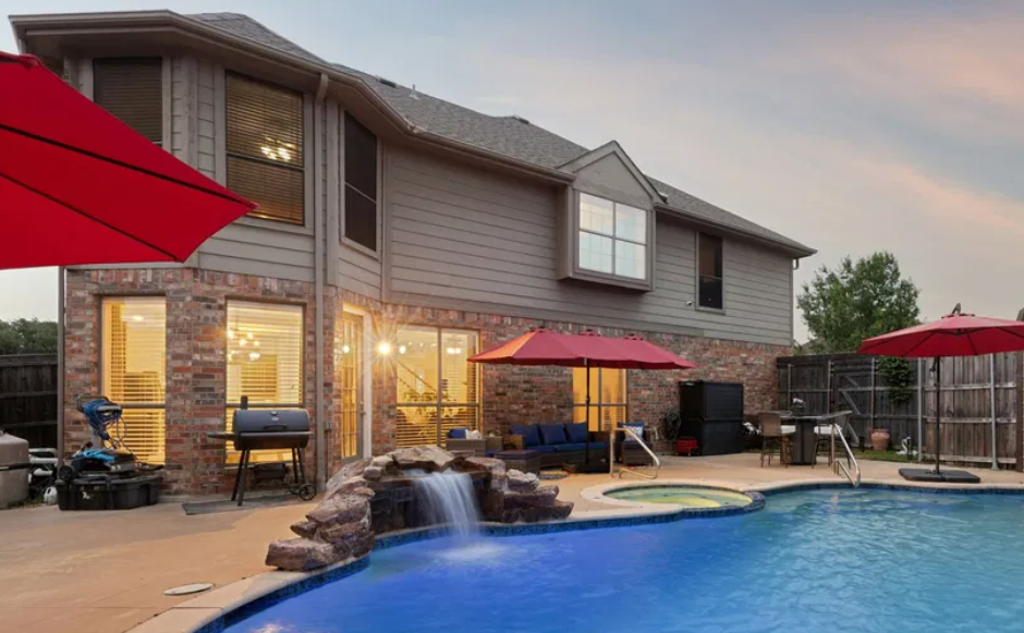 Pool and outdoor living at dusk behind a Timbers home in Murphy, Texas