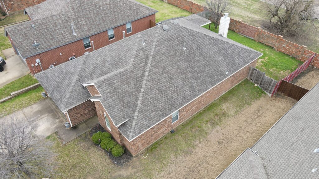 Overhead view of a brick ranch with a gray architectural-shingle hip roof, a backyard, and a wood fence in a Celina, Texas neighborhood