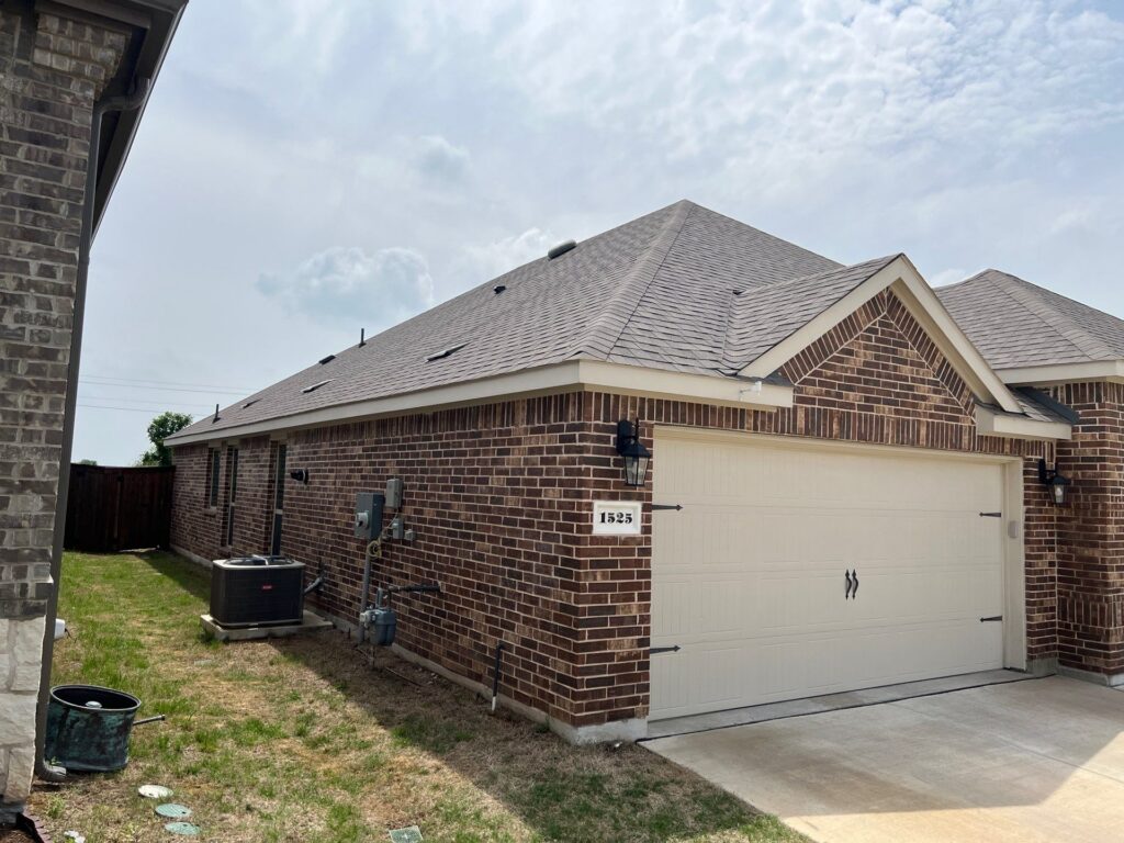 Side view of a red-brick ranch with a gray architectural-shingle hip roof and a white garage door in a Celina, Texas neighborhood